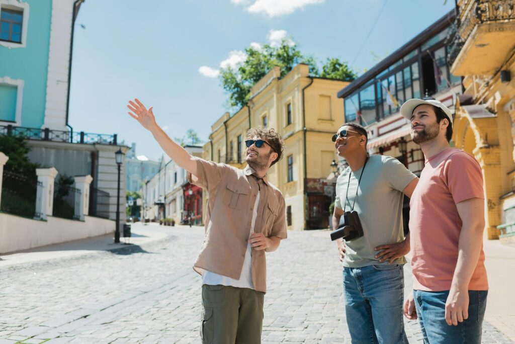 tour guide in sunglasses pointing with hand during excursion with interracial tourists on Andrews