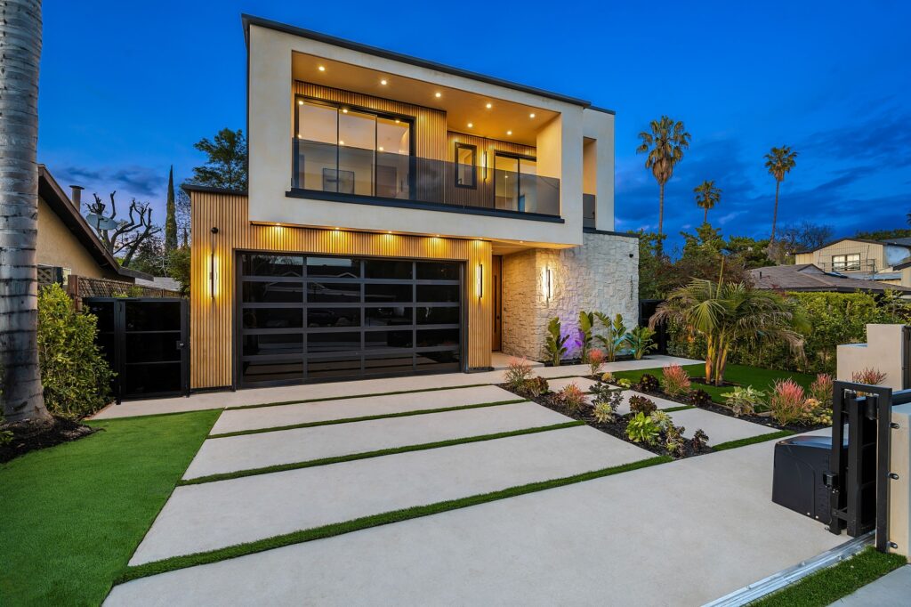 Modern two-story house with large windows and palm trees at dusk.